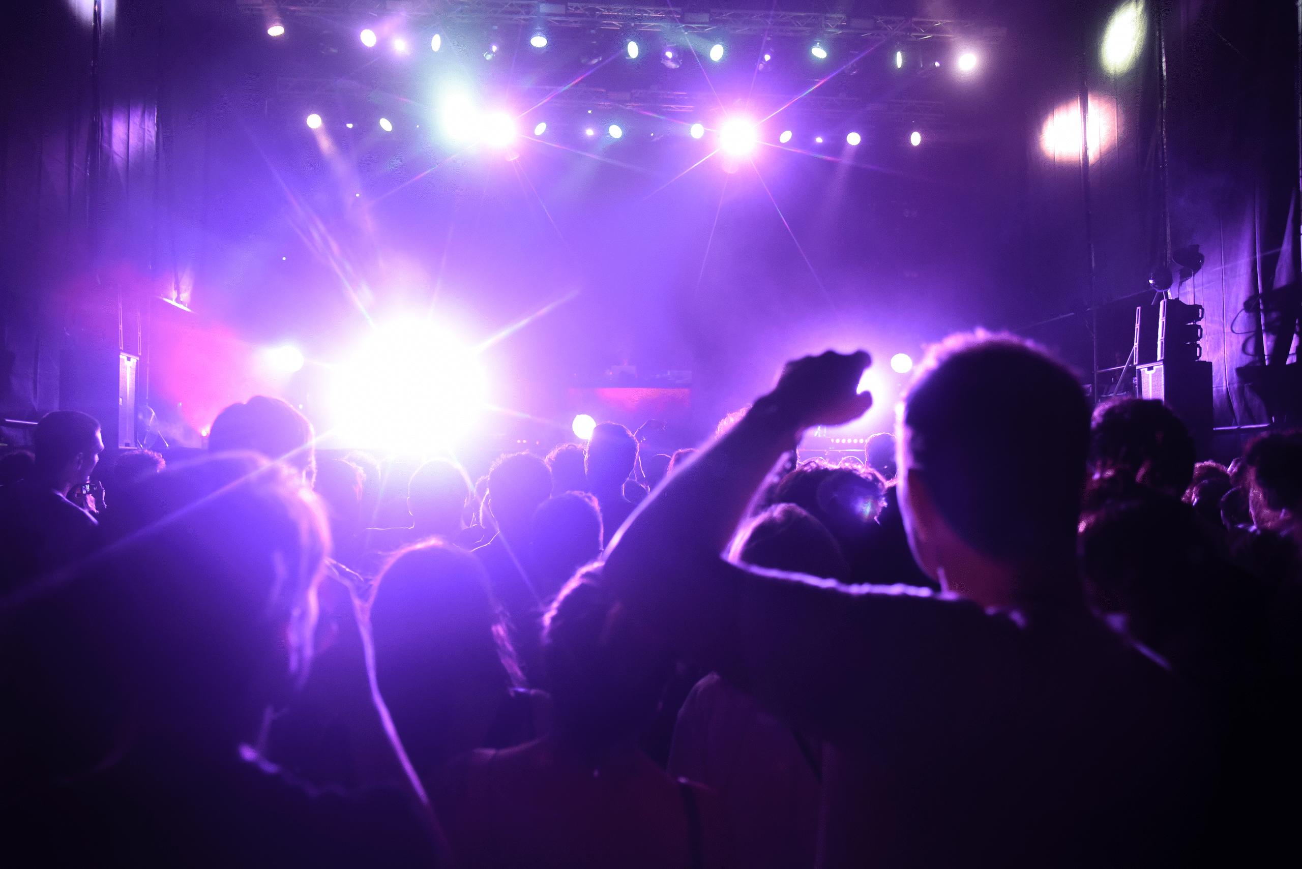 Concert crowd with raised hands in orange lighting