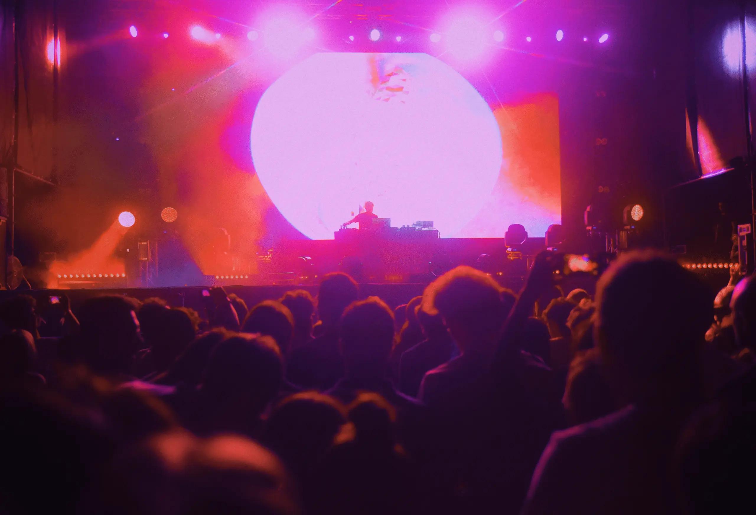 Concert crowd with raised hands in orange lighting